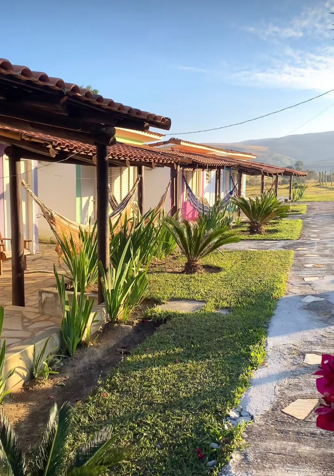 Vila Pequi, chalés coloridos lado a lado com redes na varanda e a serra ao fundo